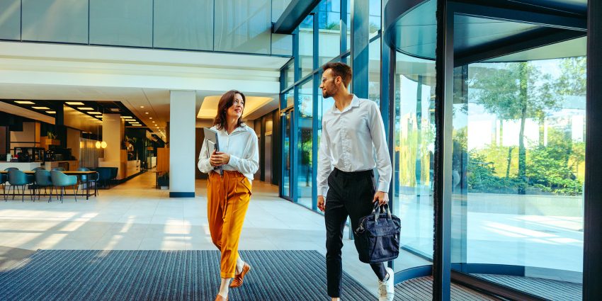 Two business professionals walking through modern corporate office lobby