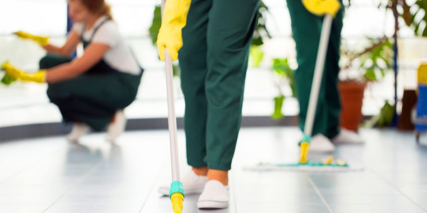 Professional cleaning crew mopping tiled floor in commercial building