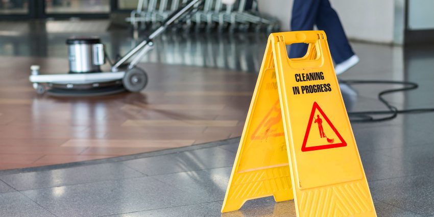 Cleaning in progress caution sign with floor buffer in commercial space