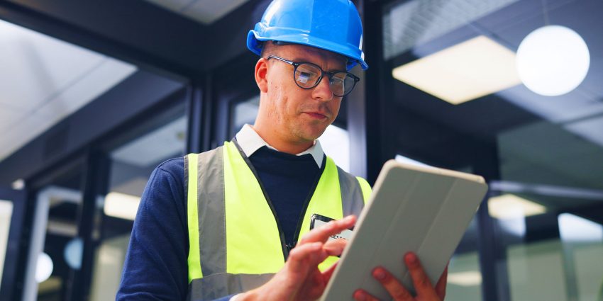 Building maintenance worker reviewing tablet in commercial hallway