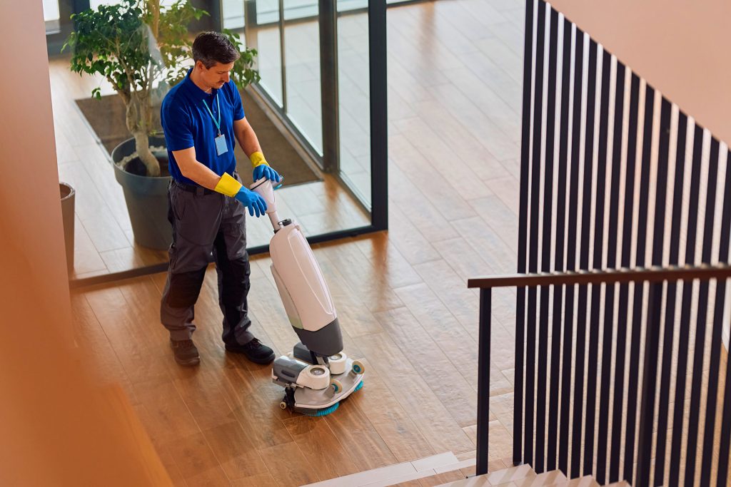 Custodian operating floor scrubber machine in office building
