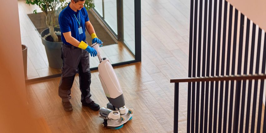 Custodian operating floor scrubber machine in office building